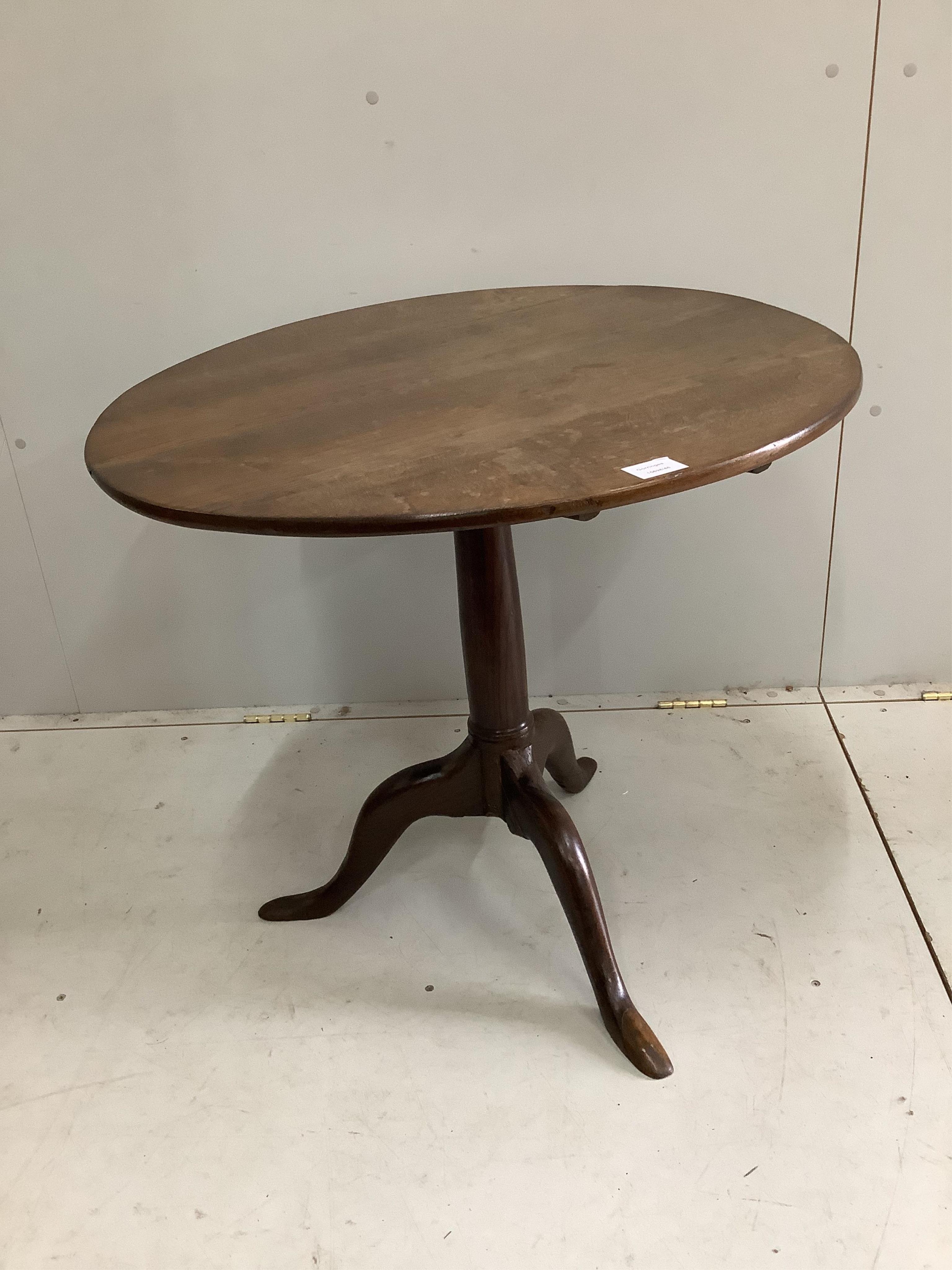 A George III circular oak tilt top tripod table, diameter 76cm. Condition - restorations